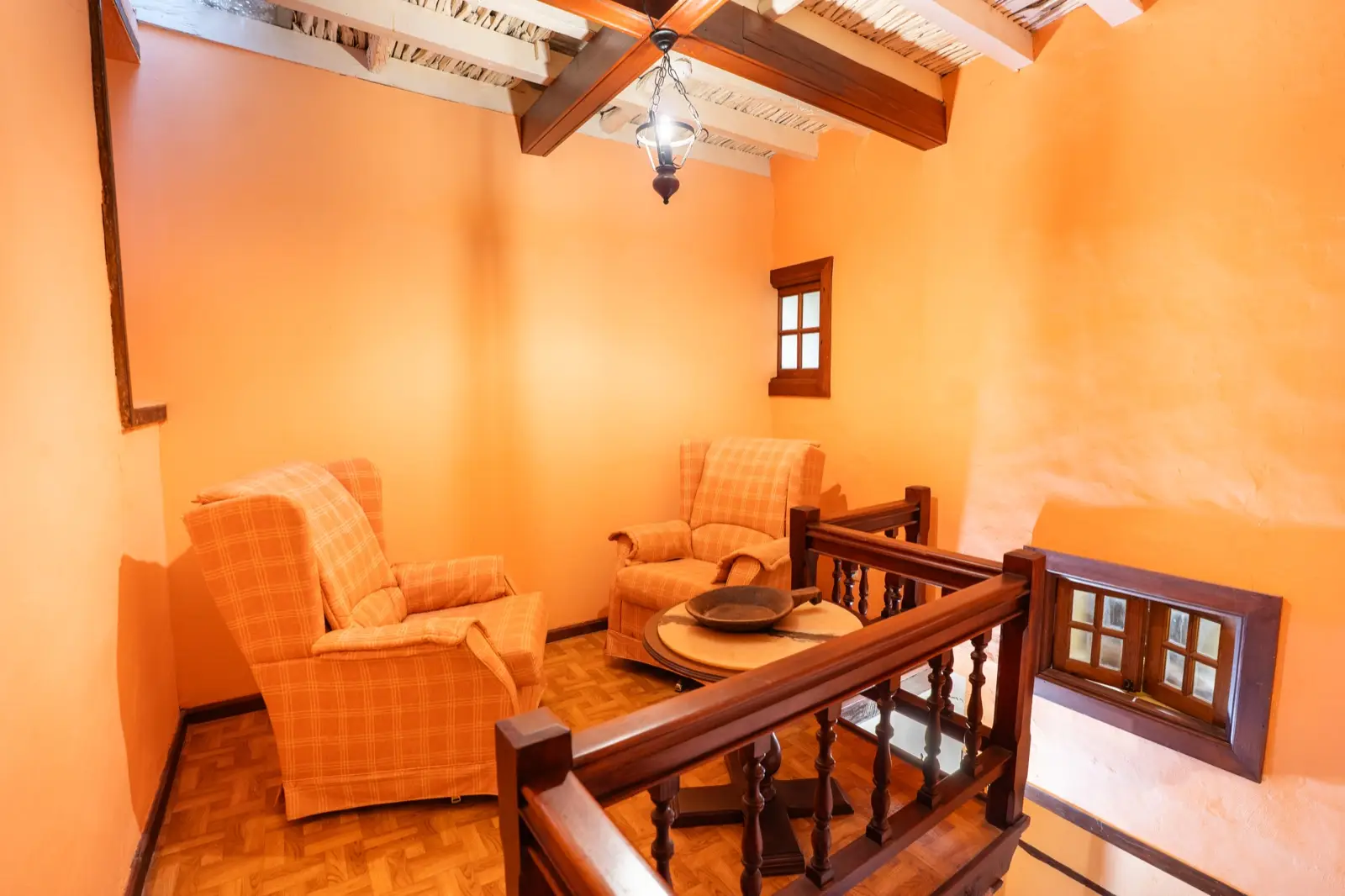 Habitación triple: rincón con dos sillones y una mesa redonda junto a la barandilla de la escalera interior