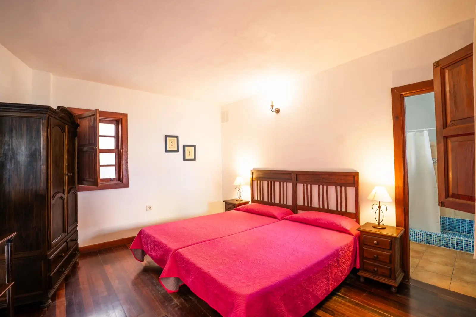 Habitación doble con dos camas individuales juntas, cabecero de madera, colchas fucsia y armario antiguo de madera oscura
